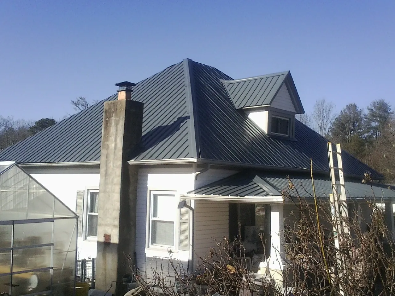 Dark blue standing seam metal roof on a white farmhouse with dormer — Slate & Tile Roof Repair by Roofing Brothers in Woodlake