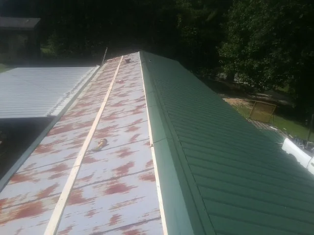 Old rusted panels beside newly installed green metal roofing — Wind Damage Roof Repair by Roofing Brothers in Woodlake