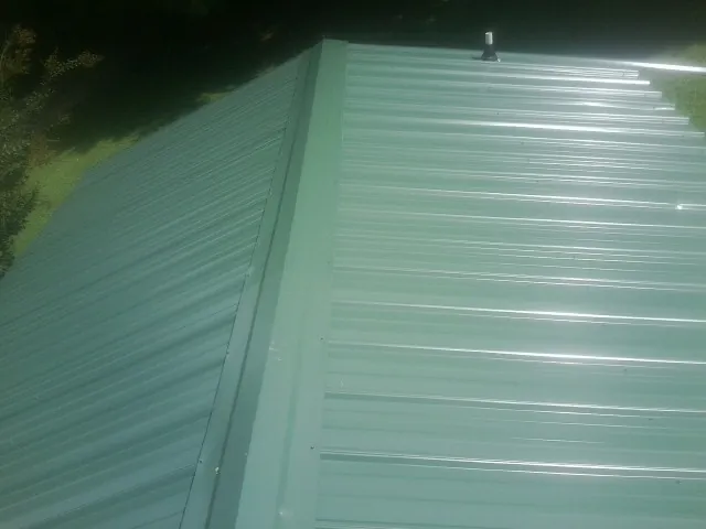 New green metal panels meeting at the ridge of a roof — Flat Roof Repair work by our crew in Woodlake
