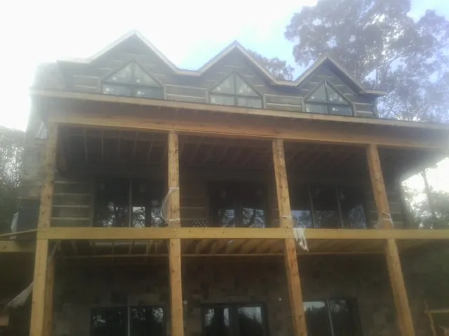 Dormers and porch framing on a large log home under construction — Roof Coating work by our crew in Woodlake