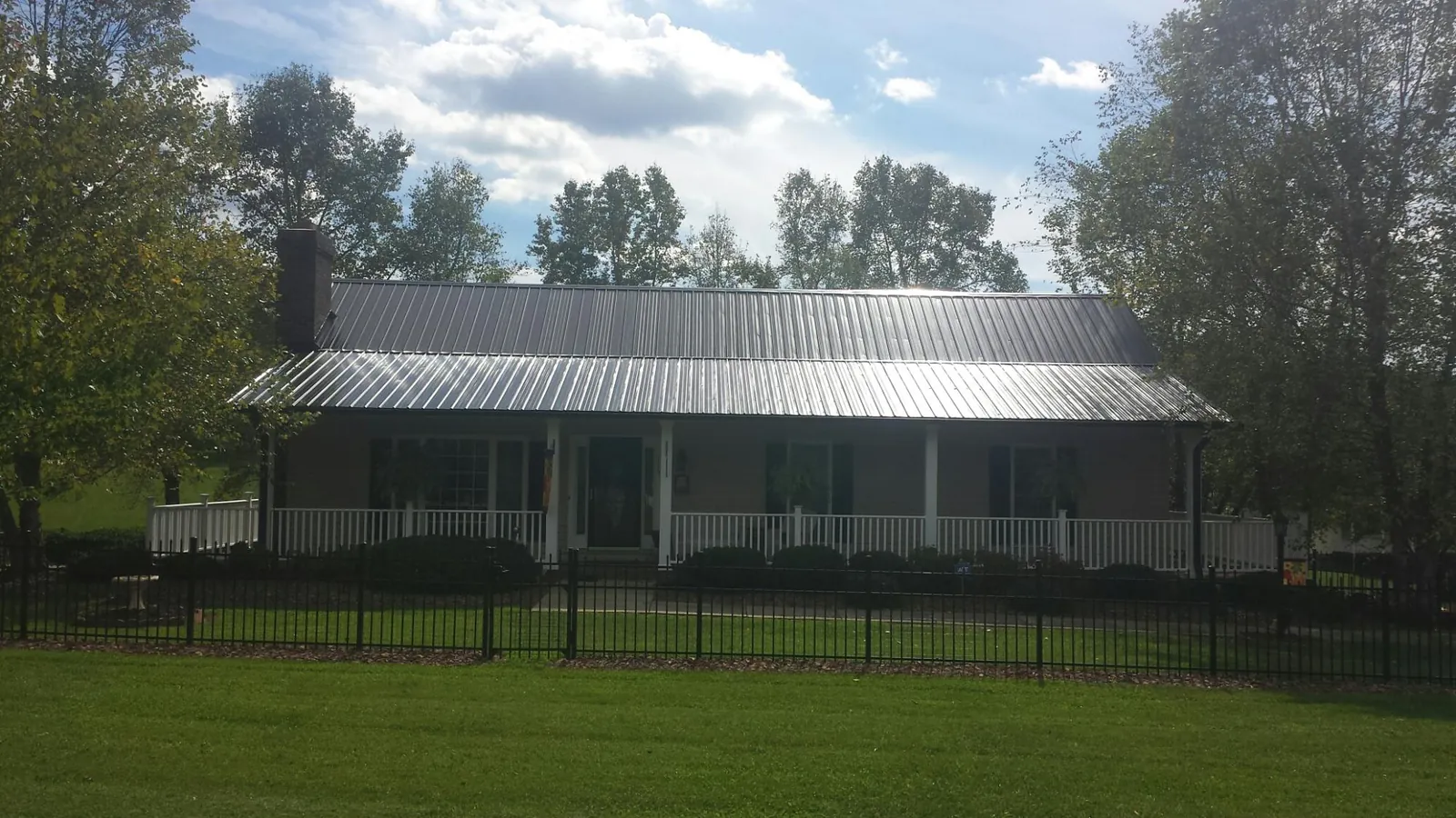 Gray metal roof on a brick ranch with a full width front porch — Gutter Guard Installation work by our crew in Woodlake