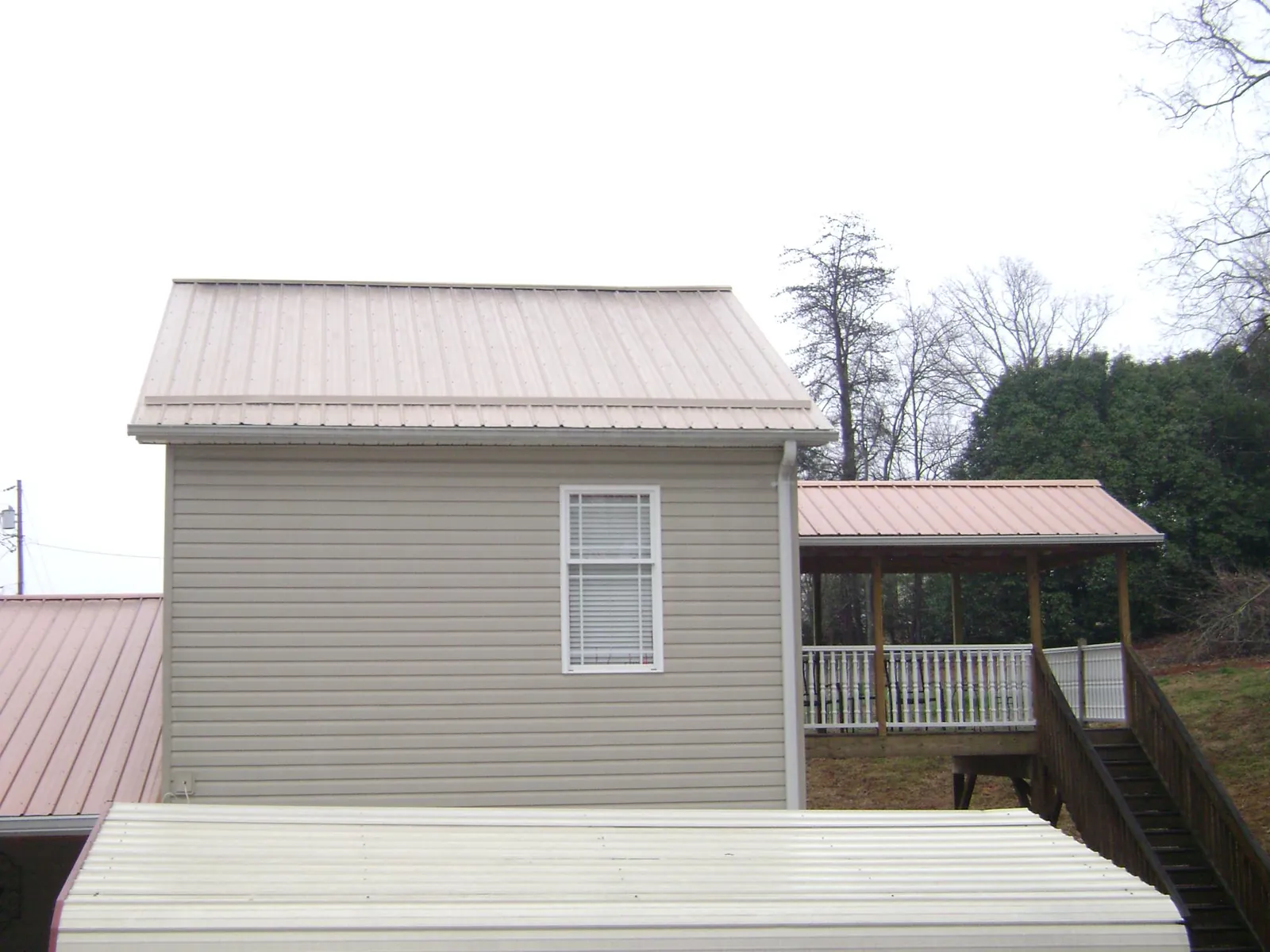 Tan metal roofs on a two story addition and attached porch, from a Roof Replacement job in Woodlake