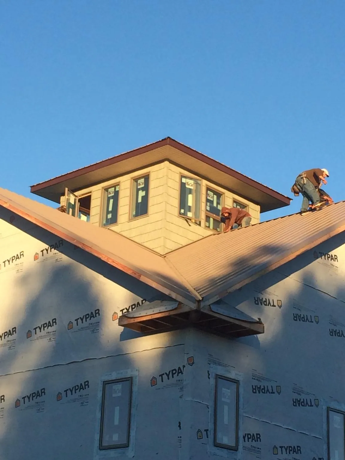 Roofers working around a rooftop cupola on a new metal roof at sunset — Roof Waterproofing in Woodlake by Roofing Brothers